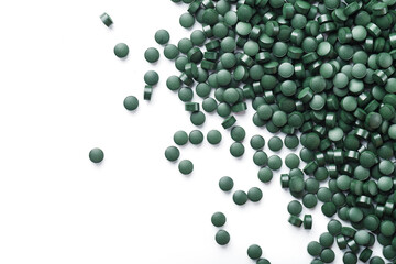 Vegetarian vitamins from Spirulina are scattered on a white background