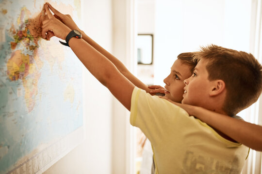 One Day We Can Travel The World Together. Shot Of Two Little Boys Looking At A Map On The Wall At Home.