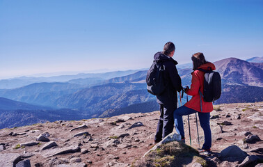 Couple hikers woman and man are enjoying landscape mountain view from the top mountain with backpack, hike sticks