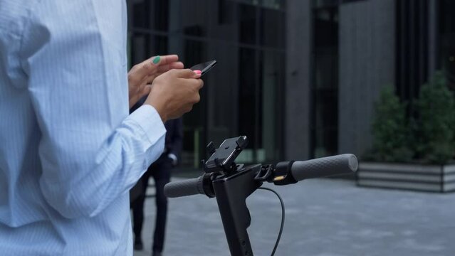 Closeup hands rent electric scooter holding smartphone. City transport concept