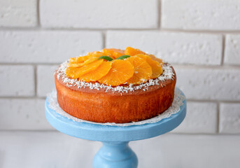 Homemade round orange sponge cake or chiffon cake garnished with orange slices on cake plate. Light...
