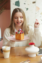 blond girl cube formed dessert with cream, raspberry, blueberry and marshmallow topping closeup...