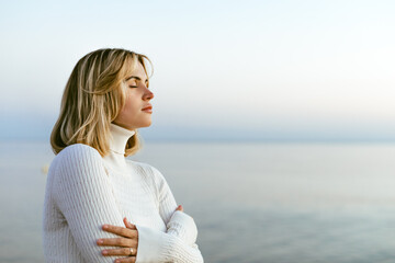 Charming calm portrait of beautiful girl in sweater on sea shore