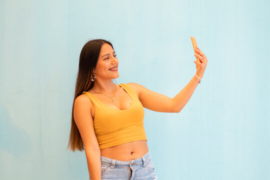 Retrato de primer plano de una atractiva joven  sonriente positiva que usa una elegante con top corto polera amarillo que se encuentran aislada sobre un fondo gris