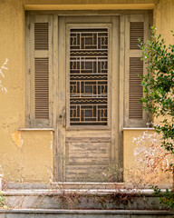 An old weathered olive green painted door and double linear window shutters