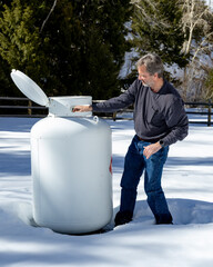 Man opens valve on a propane take in winter