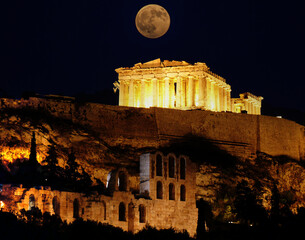 A full moon over Athens Acropolis with Parthenon temple and arches of the roman Hadrian's...