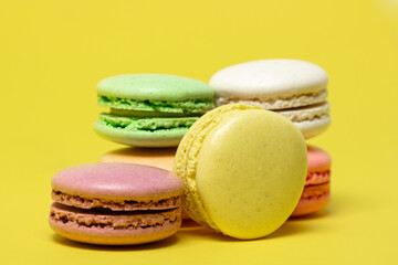 Colored macarons on a yellow background. Light and tasty dessert. traditional dessert