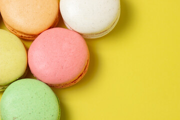 Colored macarons on a yellow background. Light and tasty dessert. traditional dessert