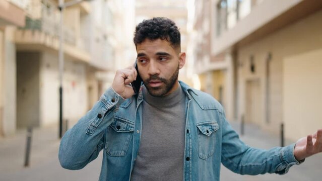 Young arab man talking on the smartphone walking at street