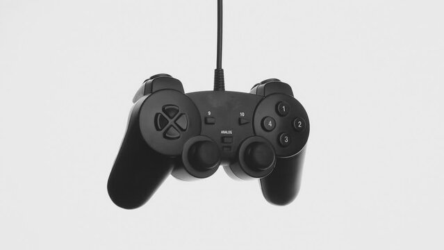 Black gamepad falls from above on a white background