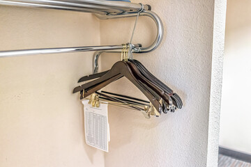 Closeup of closet hangers in empty room on pole stand in modern hotel or house room with note paper...