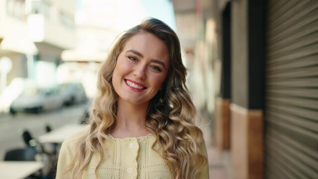 Young blonde woman smiling confident standing at street