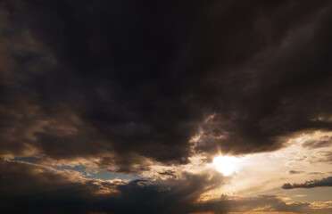 dark dramatic sky, bright sunlight and black silhouette of clouds as background