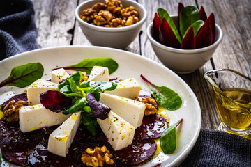 Beetroot carpaccio with goat cheese, greens and walnuts on wooden background
