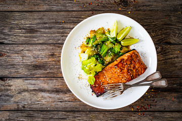 Fried teriyaki salmon steak with pak choi and lime on wooden table
