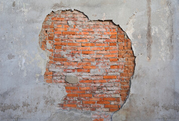 Old and aged wall with flaking plaster and brickwork made of orange brick. Texture and structure of surface. Building detail. Central composition