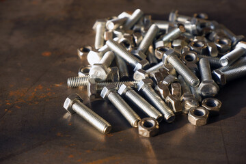 Shiny bolts and nuts on a steel table close-up.