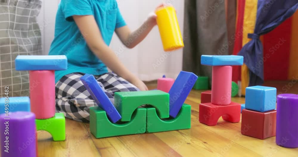 Poster a child is playing with children building blocks on floor. building a tower of cubes. educational to