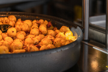 Traditional Polish potatoes with pork rinds in a large frying pan at a food festival in Krakow. Close-up, side view from above