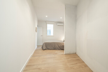 Room with a double bed with a gray duvet, a space to mount a built-in wardrobe and oak flooring.