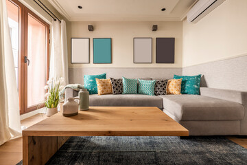 Living room with designer pine table, three-seater sofa with chaise longue with cushions of many colors and access to the terrace through an aluminum and glass window