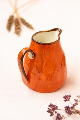 Milk in an orange jar, spikelet, herbs on white background. Milk pitcher for package design., cream...
