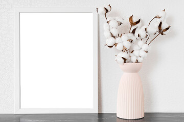 white empty frame for text, vase with cotton flowers on white wall on black marble table