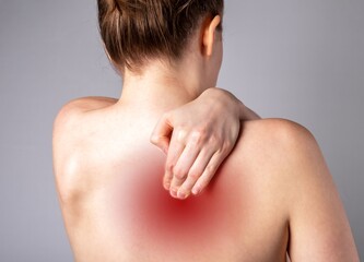 Pain between shoulder blades. Woman suffering from backache with red spot closeup. Spine diseases, injuries, arthritis, scoliosis, pinched nerve. Health care concept. High quality photo - obrazy, fototapety, plakaty
