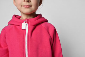 Close-up of a child in a pink jumpsuit or sweatshirt with a zipper, headless photo. Shoulders, neck