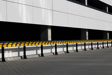 Yellow and black guardrails outside building, parking lot.