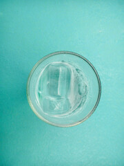 Shape of drinking glass top view with ice isolated on aqua green background