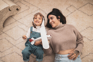 The happy family is having fun at home. Mother and her child playing together. Child dressed as a...