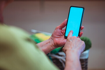 Close up of a wrinkled hands of a senior woman holding a smartphone