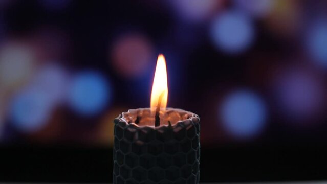 Blue magic wax candle strewn with grass, ritual candle of memory and cleansing of the house, beautiful decor item, bokeh background