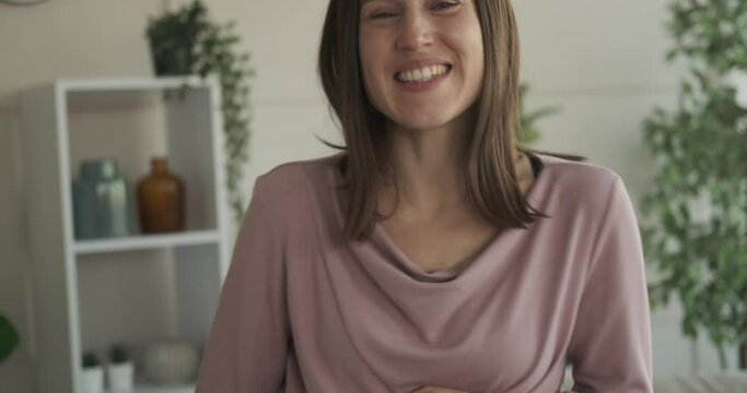 Pregnant woman caressing her belly while singing and dancing at home