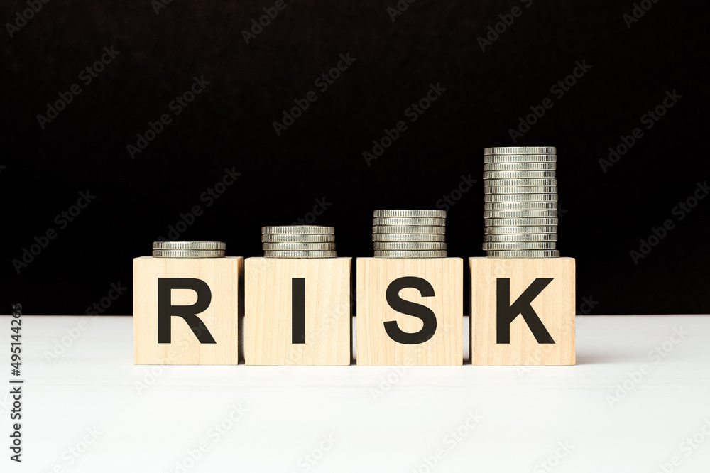 Poster there are four wooden cubes with letters on the white table. risk word. black background with increa