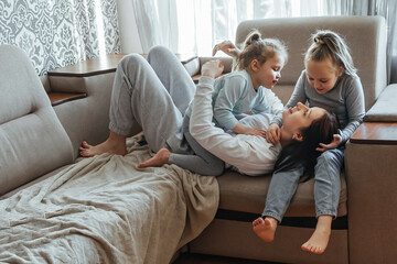 Two children, little girls hug their older sister tightly, show their love and feelings in a warm home environment