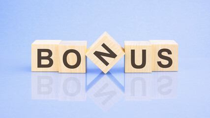 text Bonus - letters by on woodens blocks on pale lilac background, in concept of business and corporation