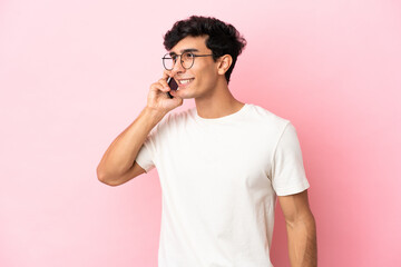Young Argentinian man isolated on pink background keeping a conversation with the mobile phone with someone