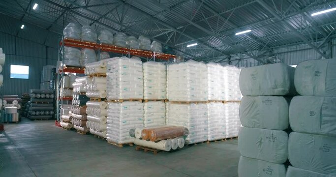 Spunbond in rolls in the warehouse of the factory. Warehouse of raw materials at the factory. Lots of raw material bag for production.