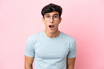 Obraz premium Young Argentinian man isolated on pink background With glasses and surprised expression