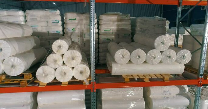 Spunbond on warehouse shelves. Rolls of padding polyester on the shelves of the warehouse. Spunbond in rolls. Non-Woven Fusible Interlining Fabric