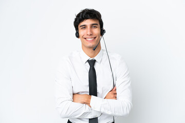 Telemarketer man working with a headset isolated on white background keeping the arms crossed in...
