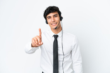 Telemarketer man working with a headset isolated on white background showing and lifting a finger