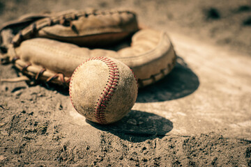 Baseball and mitt on home plate of ball field