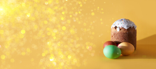 A banner with colored Easter eggs and a cake on a yellow background with a golden sheen. With a place to copy. Orthodox Easter. High quality photo