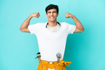 Young electrician Argentinian man isolated on blue background doing strong gesture