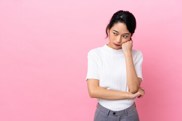 Young Vietnamese woman isolated on pink background with tired and bored expression