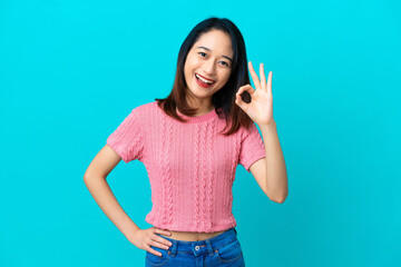 Young Vietnamese woman isolated on blue background showing ok sign with fingers